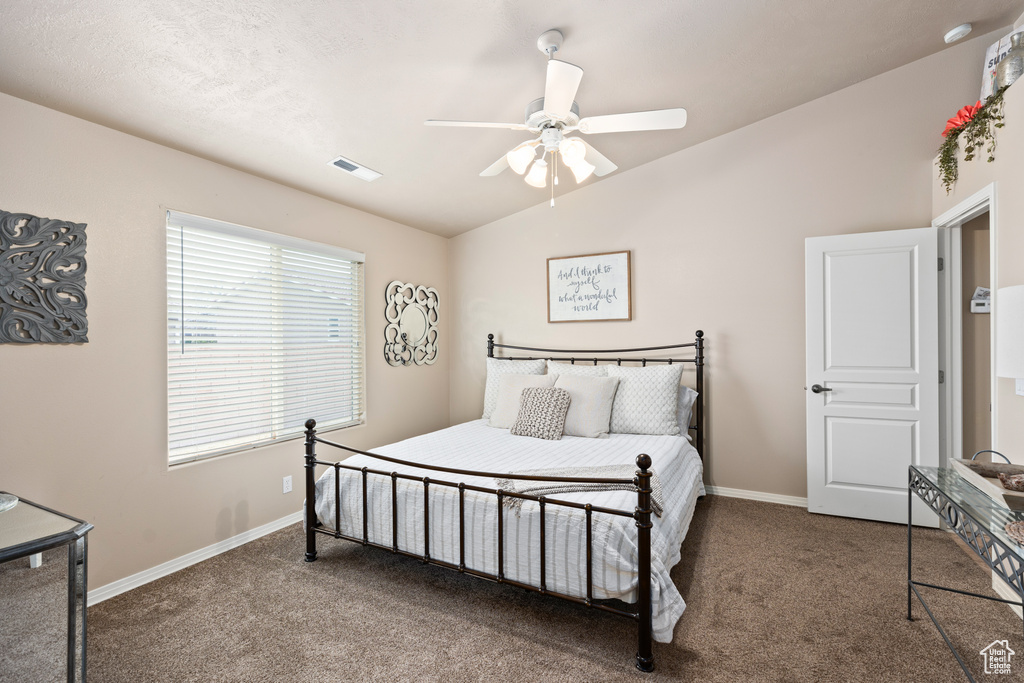 Bedroom with vaulted ceiling, dark carpet, and ceiling fan