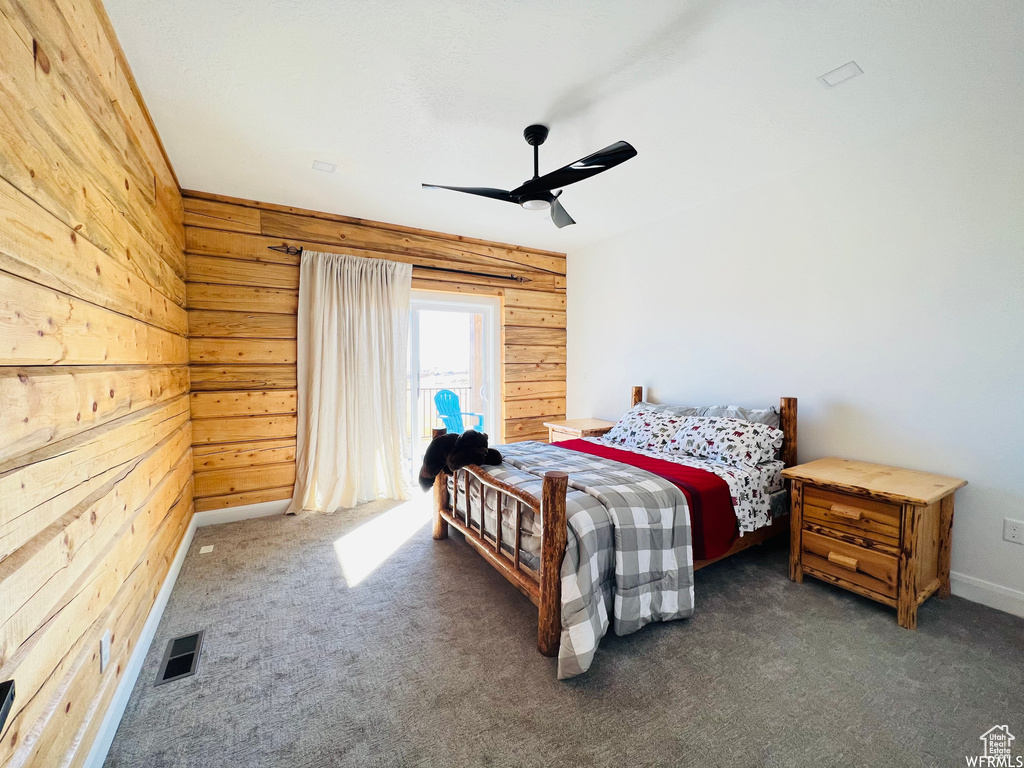 Bedroom featuring wood walls, dark colored carpet, access to outside, and ceiling fan