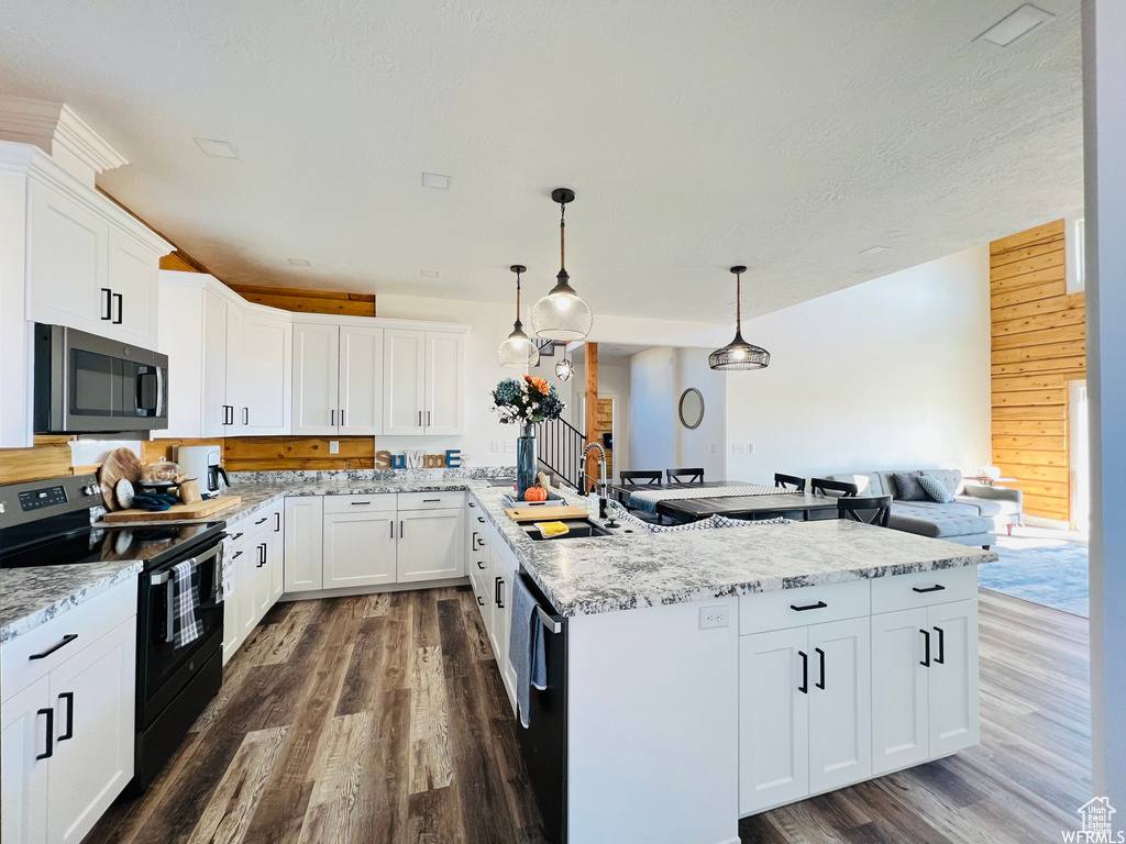 Kitchen featuring pendant lighting, electric range oven, white cabinetry, and wooden walls
