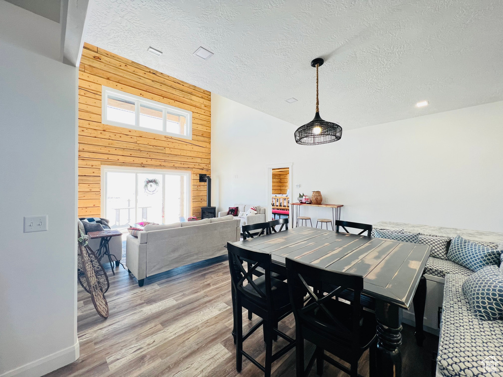 Dining space with a textured ceiling, wood walls, and light hardwood / wood-style flooring