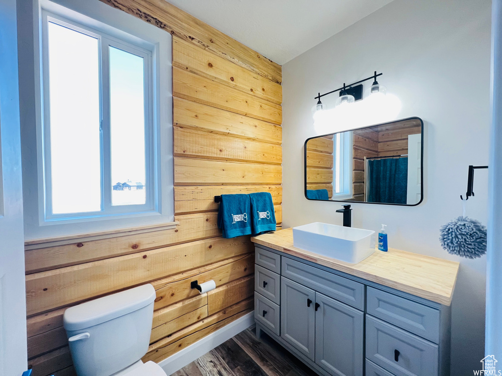 Bathroom featuring wood-type flooring, toilet, vanity, and wooden walls