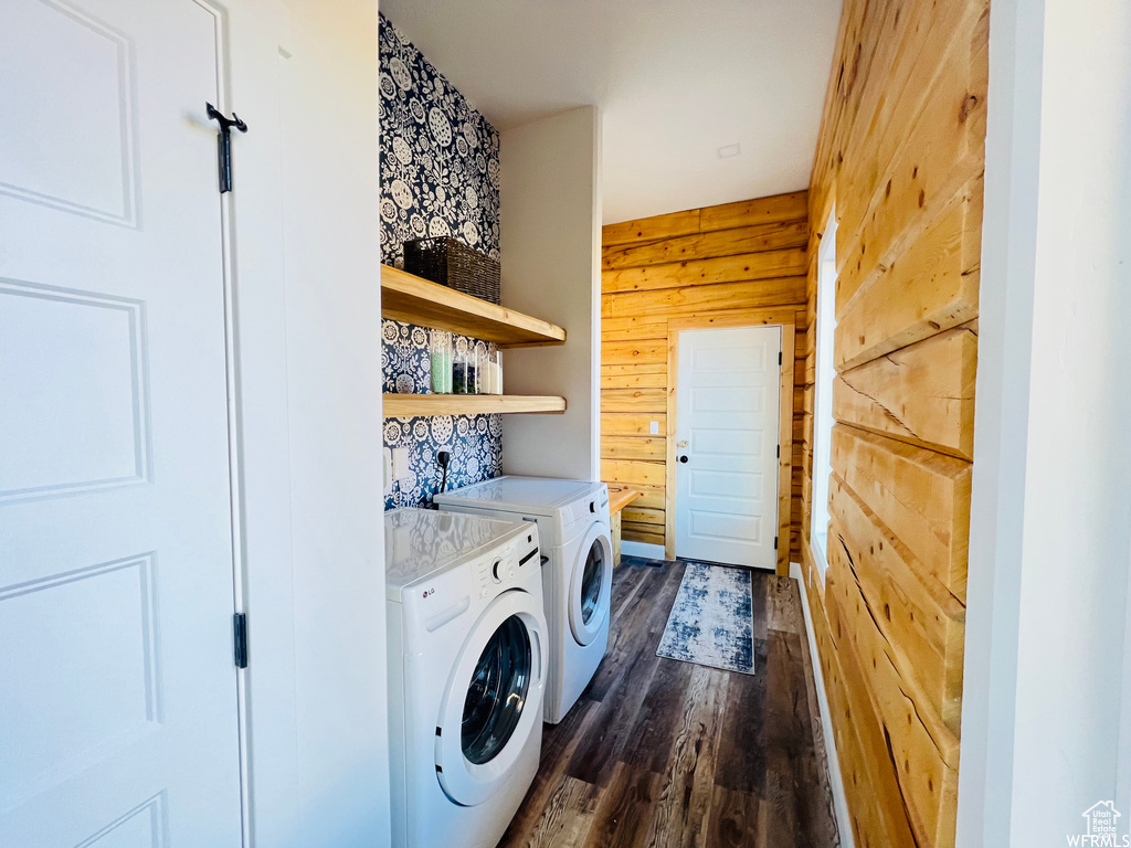 Laundry area with dark hardwood / wood-style flooring, washer and dryer, and wooden walls