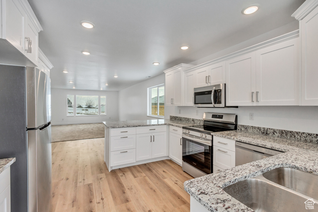 Kitchen featuring white cabinetry and appliances with stainless steel finishes