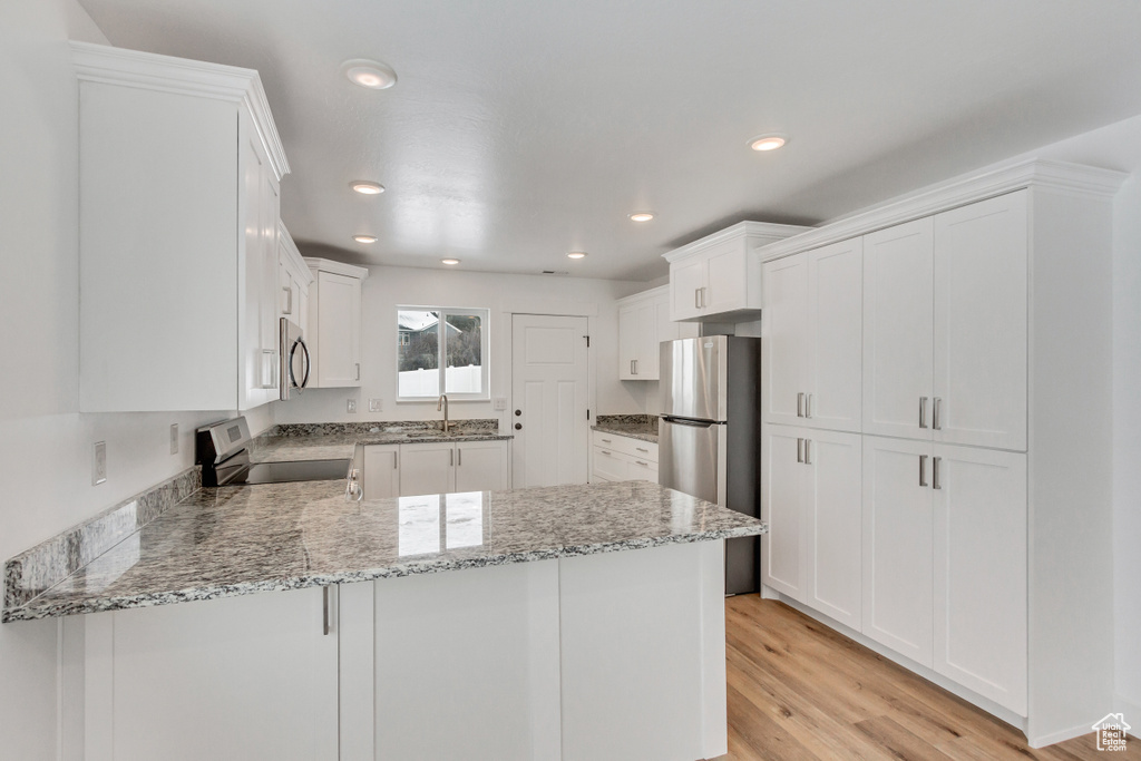 Kitchen featuring white cabinets, appliances with stainless steel finishes, and light stone counters