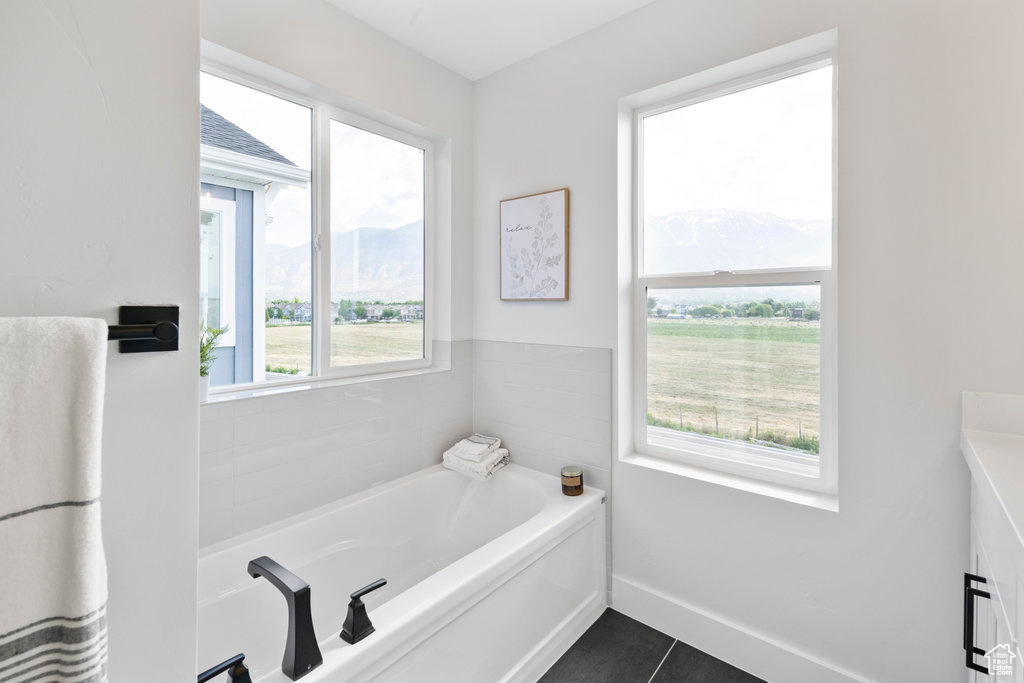 Bathroom featuring plenty of natural light, a bathtub, and tile flooring