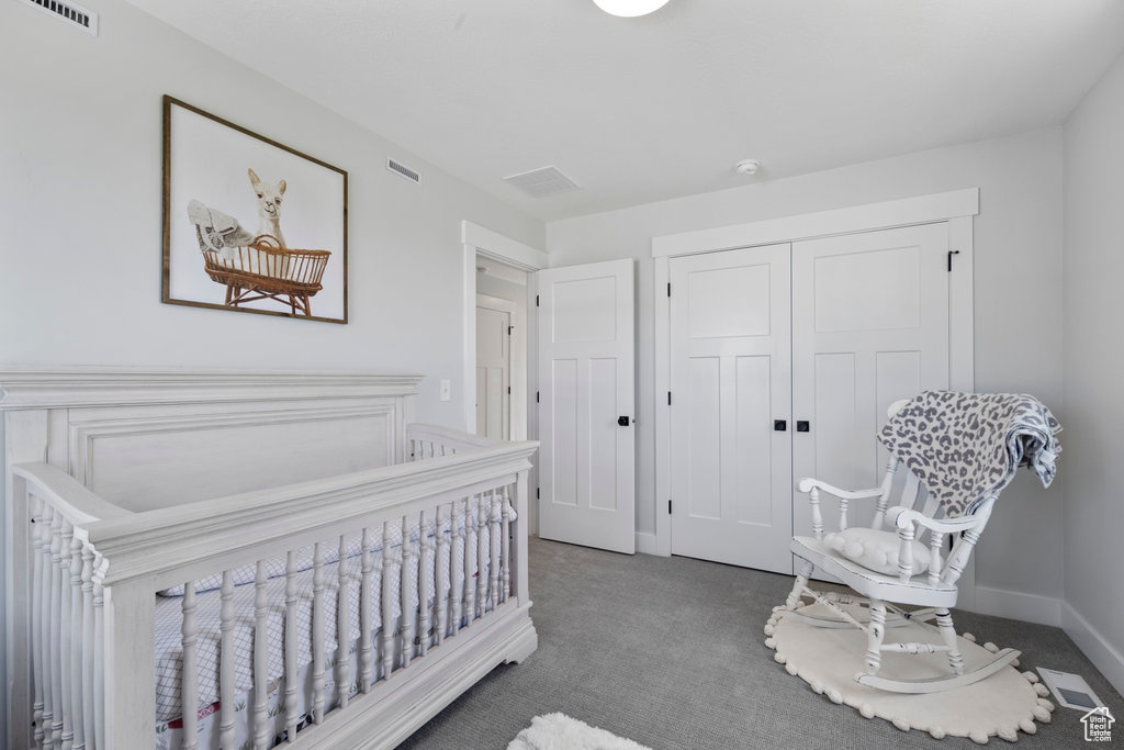 Bedroom featuring a crib, a closet, and dark colored carpet