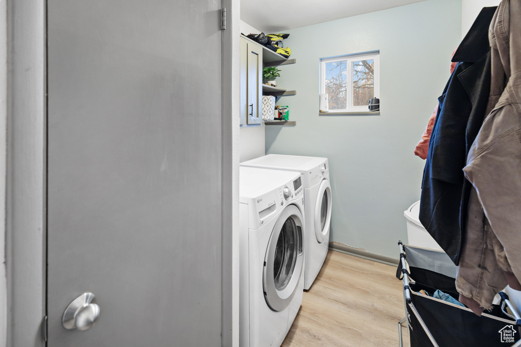 Laundry room with light hardwood / wood-style floors and washer and clothes dryer