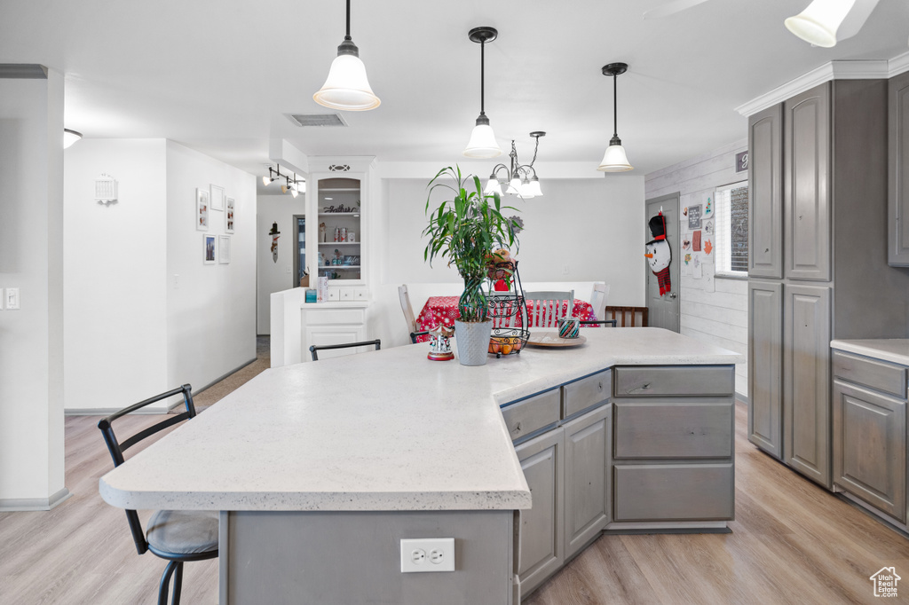 Kitchen with pendant lighting, light hardwood / wood-style floors, and a kitchen island
