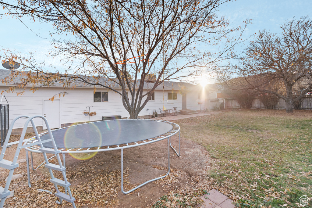 Rear view of property with a lawn, a patio, and a trampoline