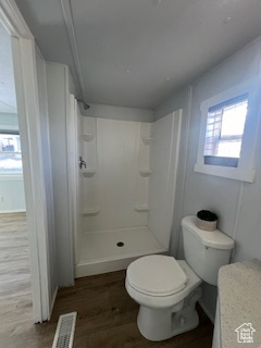 Bathroom featuring hardwood / wood-style floors, toilet, and walk in shower