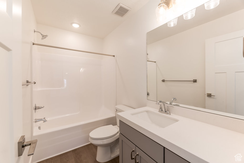 Full bathroom featuring toilet, shower / bathing tub combination, hardwood / wood-style flooring, and vanity