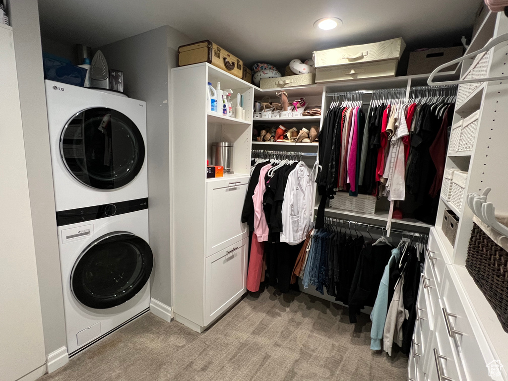 Spacious closet with light colored carpet and stacked washer and clothes dryer