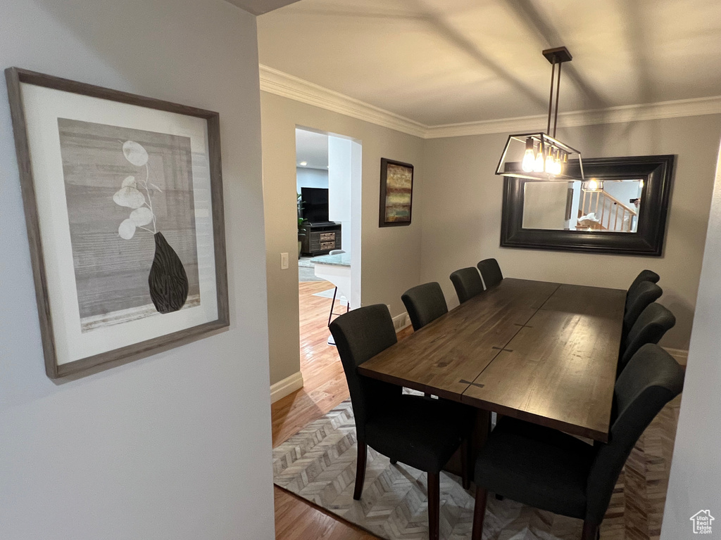 Dining room with ornamental molding and hardwood / wood-style flooring