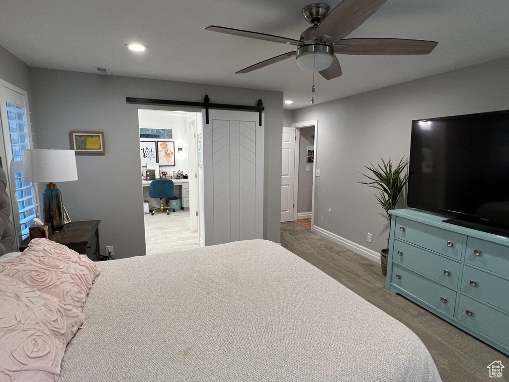 Bedroom with carpet flooring, a barn door, and ceiling fan