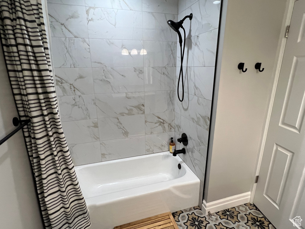 Bathroom featuring tile flooring and shower / bathtub combination with curtain