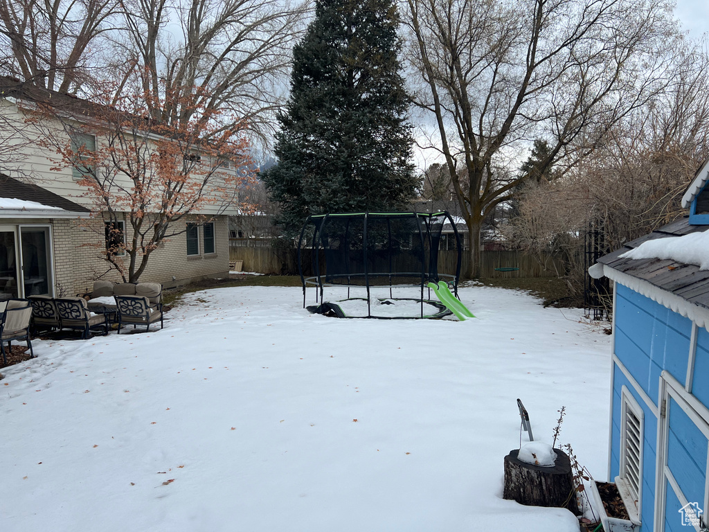 Snowy yard featuring a trampoline