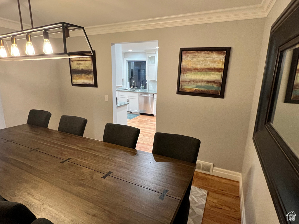 Dining space with crown molding, light hardwood / wood-style floors, and sink