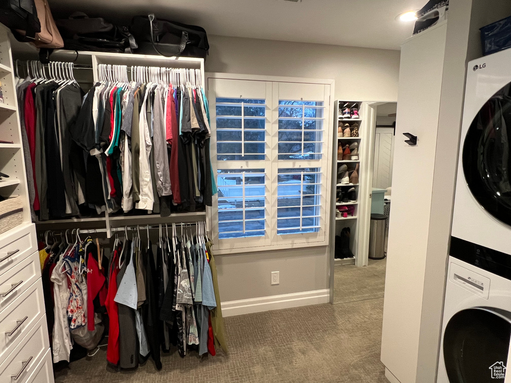 Spacious closet with stacked washer / drying machine and dark carpet