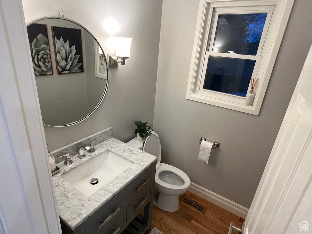 Bathroom with hardwood / wood-style floors, toilet, and vanity
