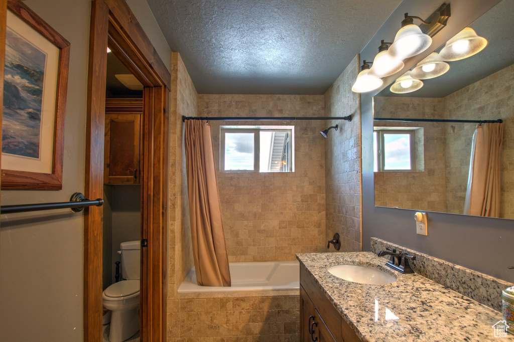 Full bathroom with shower / bath combo, toilet, vanity with extensive cabinet space, and a healthy amount of sunlight
