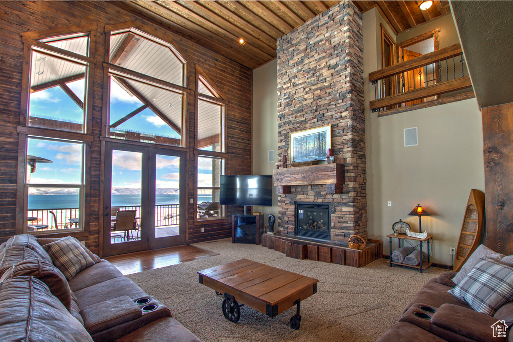 Living room with a fireplace, french doors, a water view, wood ceiling, and high vaulted ceiling