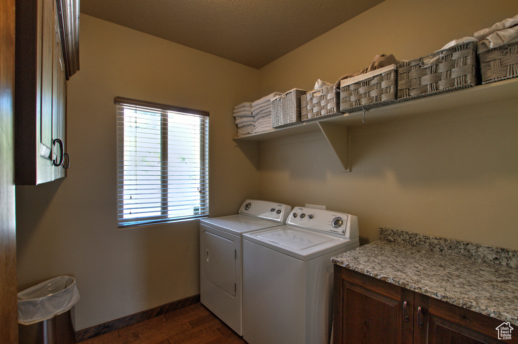 Laundry area with washing machine and clothes dryer, dark hardwood / wood-style floors, cabinets, and a healthy amount of sunlight