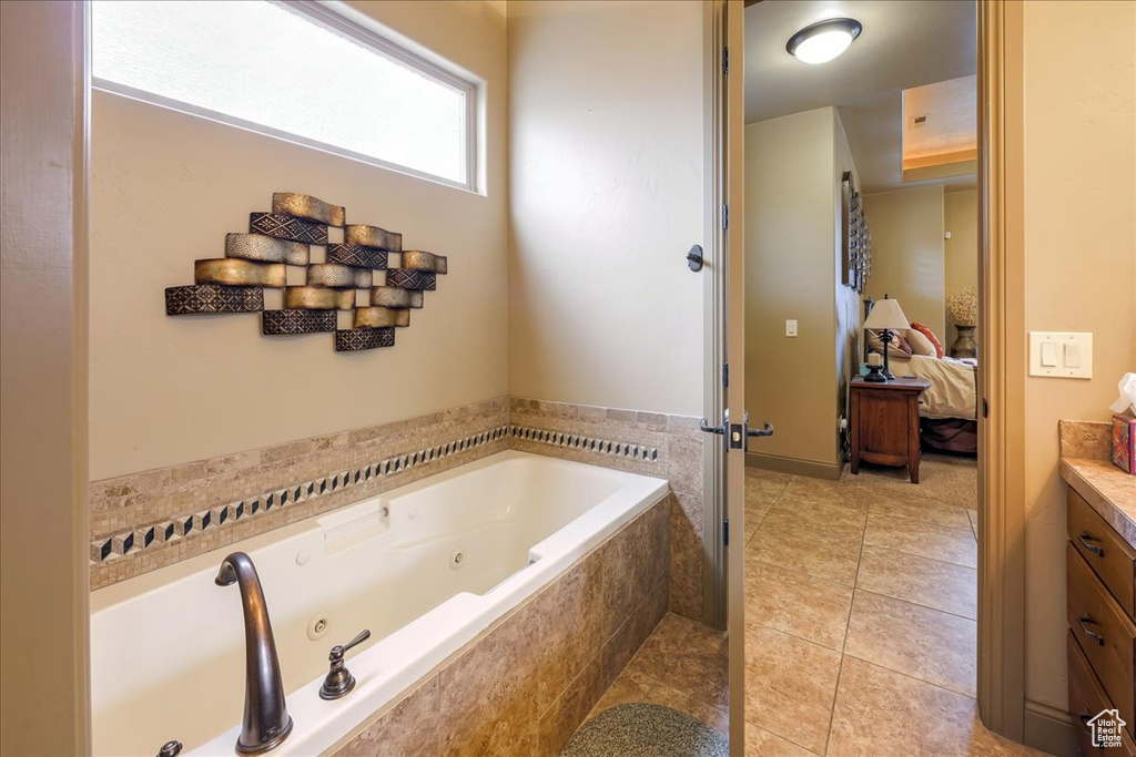 Bathroom with tiled tub, vanity, and tile floors