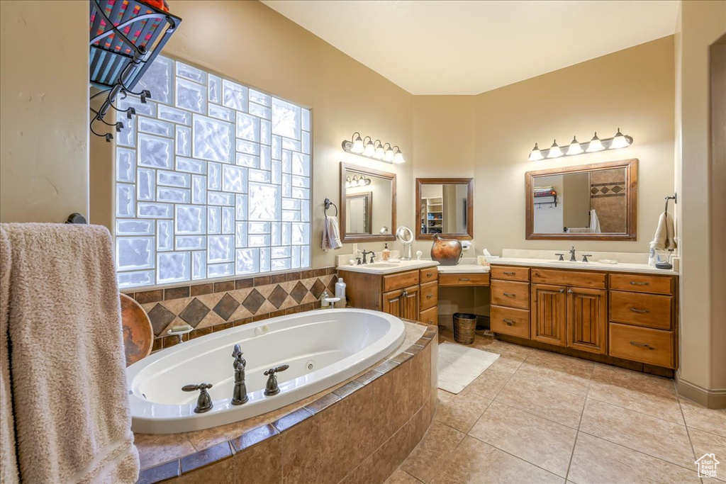 Bathroom with tiled tub, tile flooring, and dual bowl vanity