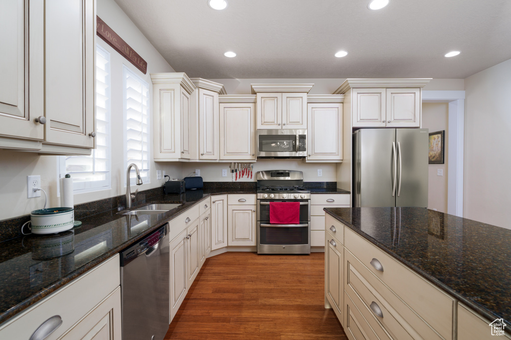 Kitchen featuring dark stone counters, hardwood / wood-style floors, sink, and appliances with stainless steel finishes