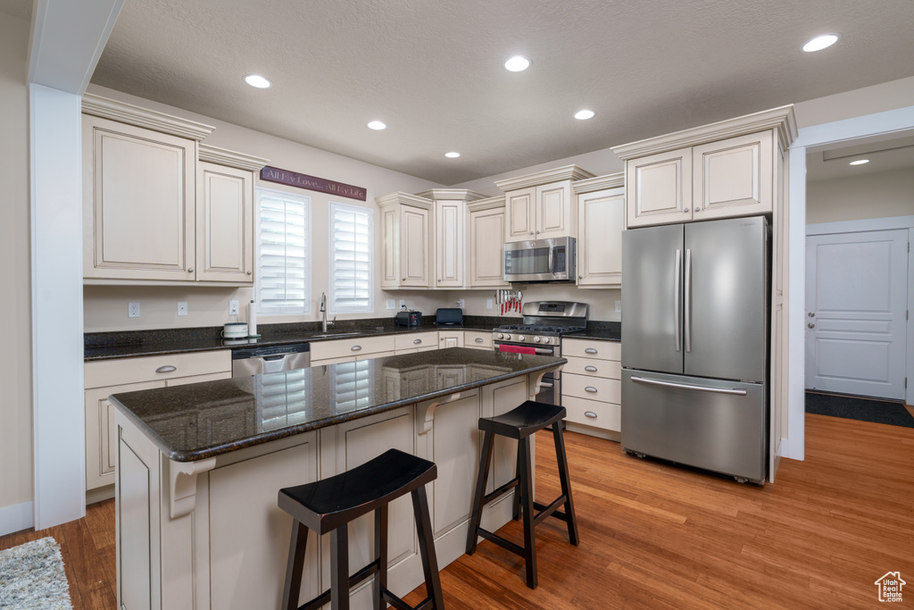 Kitchen with a breakfast bar area, appliances with stainless steel finishes, a center island, and light hardwood / wood-style flooring