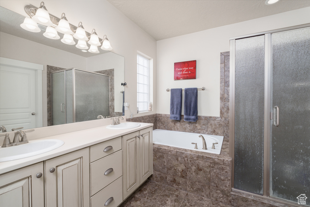 Bathroom featuring tile floors, large vanity, plus walk in shower, and double sink