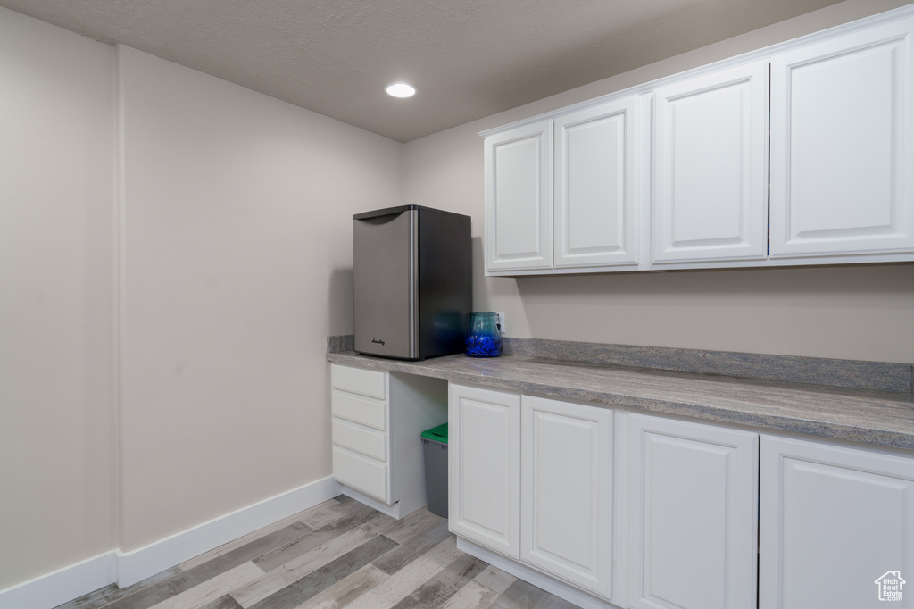 Kitchen featuring white cabinets, built in desk, and light hardwood / wood-style flooring