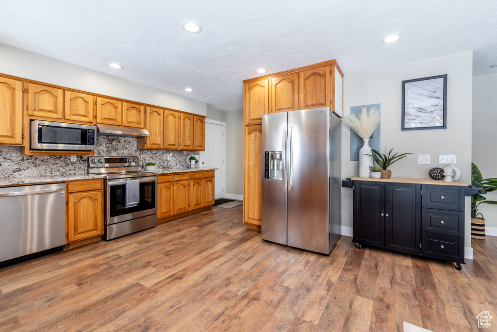 Kitchen featuring appliances with stainless steel finishes, backsplash, and hardwood / wood-style floors