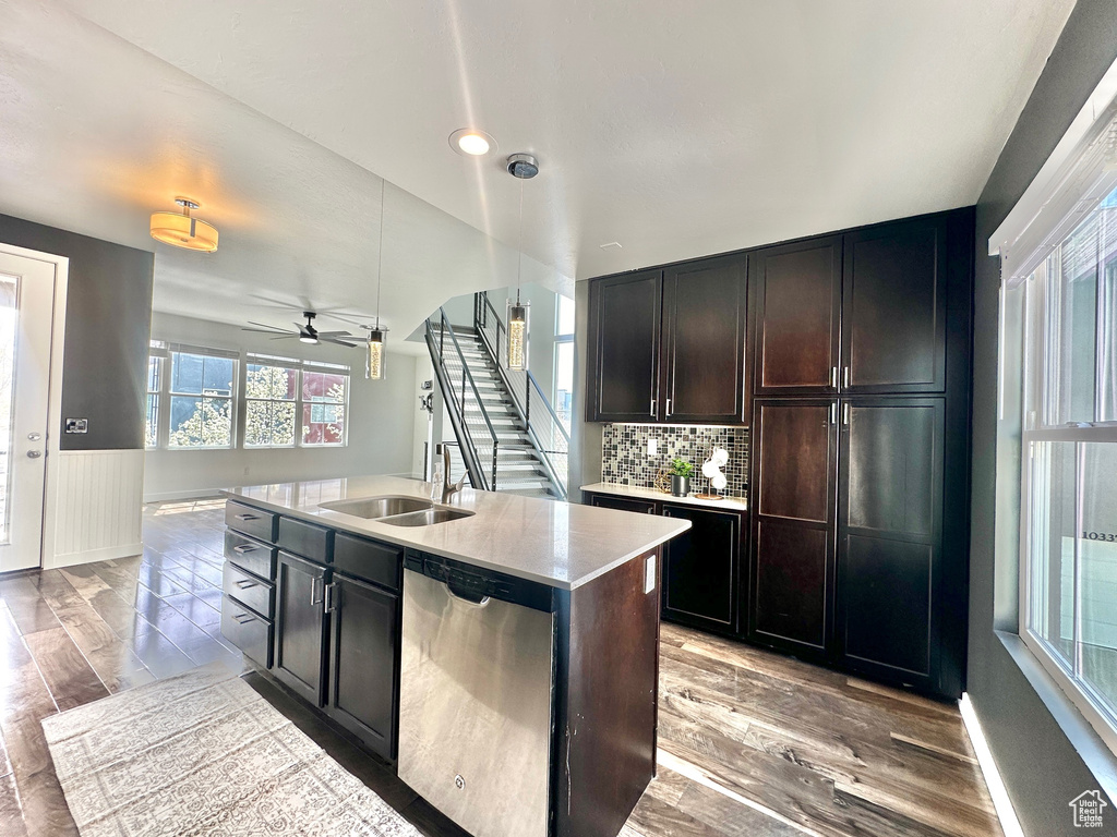 Kitchen featuring a kitchen island with sink, stainless steel dishwasher, tasteful backsplash, light hardwood / wood-style floors, and ceiling fan