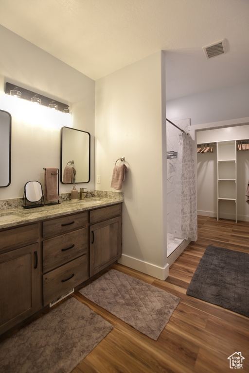 Bathroom featuring wood-type flooring, dual bowl vanity, and walk in shower