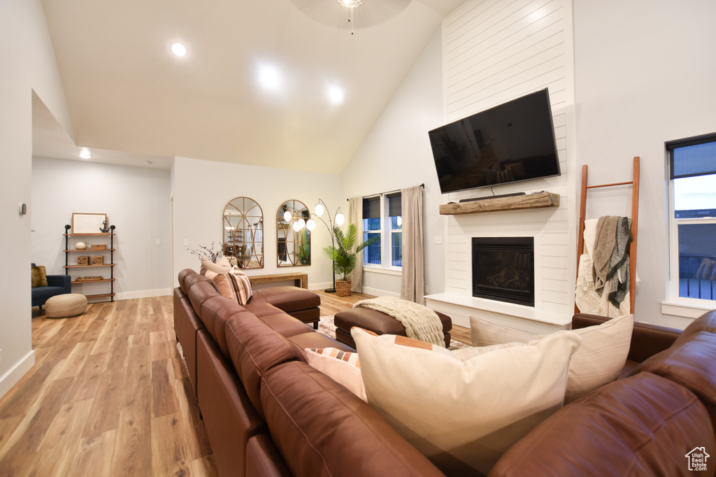 Living room with light wood-type flooring, high vaulted ceiling, and ceiling fan