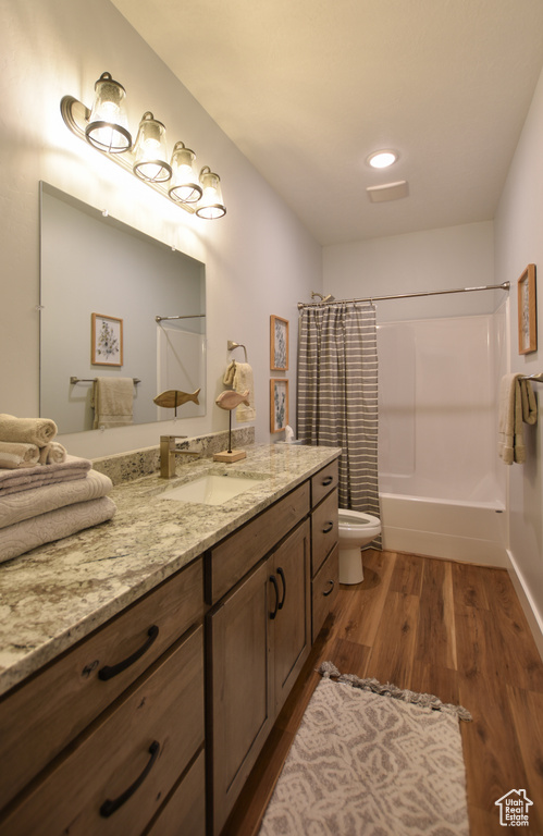 Full bathroom with vanity, shower / tub combo with curtain, toilet, and hardwood / wood-style floors