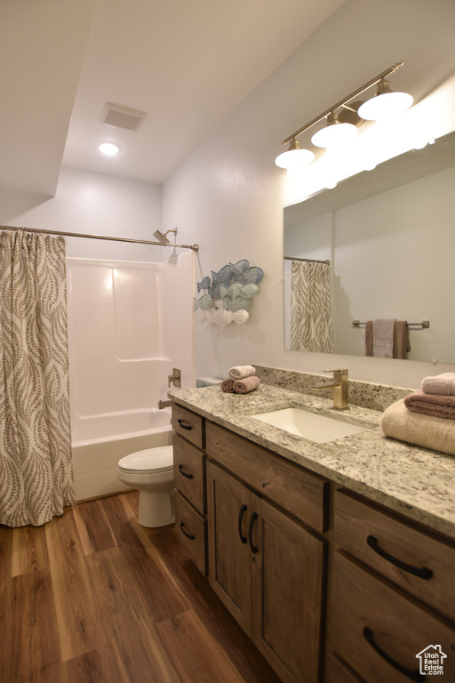 Full bathroom featuring wood-type flooring, vanity, toilet, and shower / tub combo