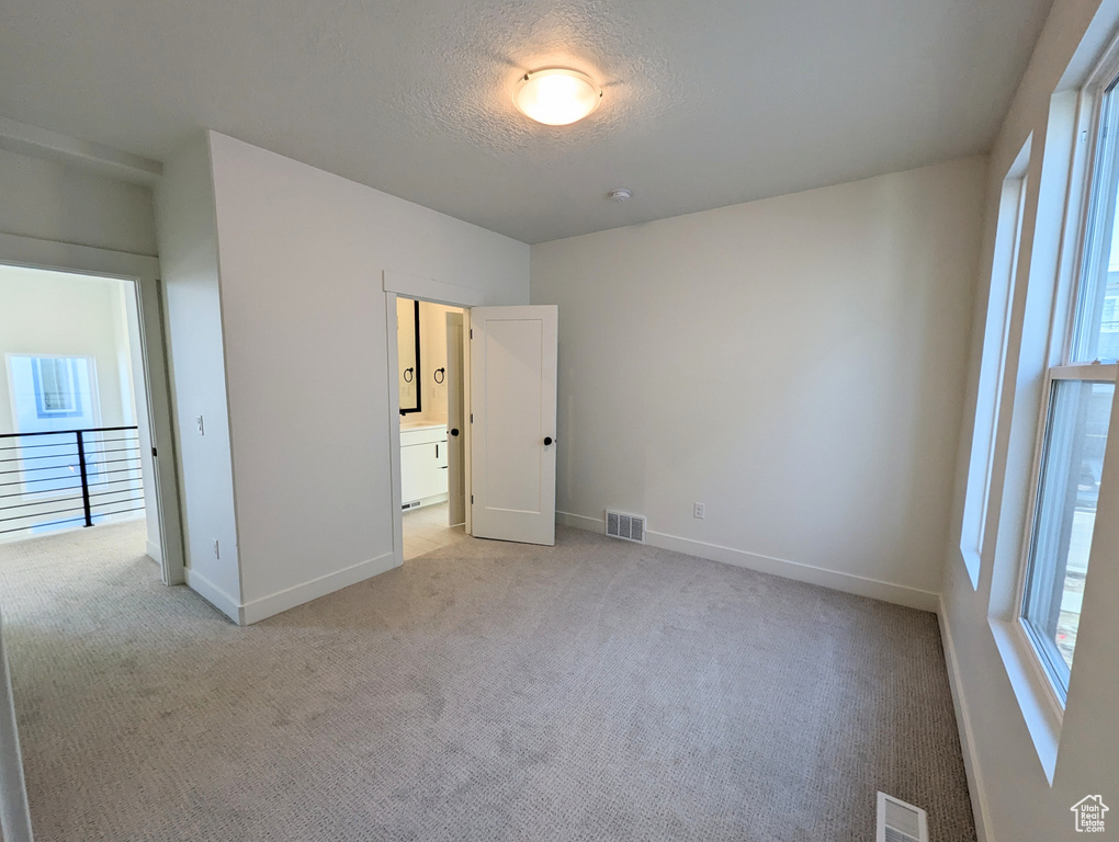 Unfurnished bedroom with light carpet and connected bathroom