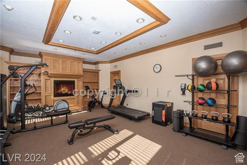 Workout area with crown molding, dark carpet, and a raised ceiling
