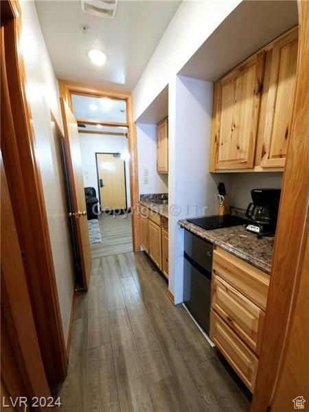 Kitchen with dark hardwood / wood-style flooring and dark stone countertops