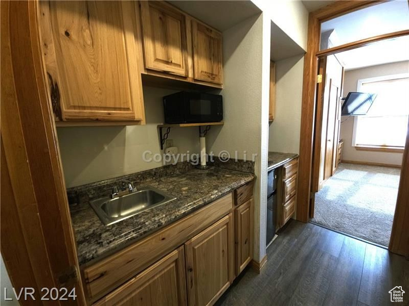 Kitchen with dark stone counters, dark hardwood / wood-style floors, and sink