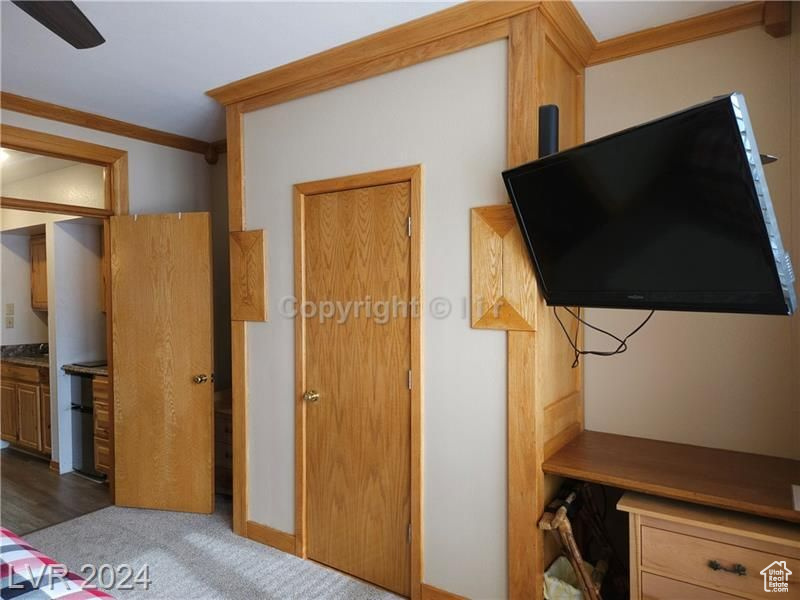 Bedroom with ornamental molding, dark carpet, ensuite bathroom, and ceiling fan