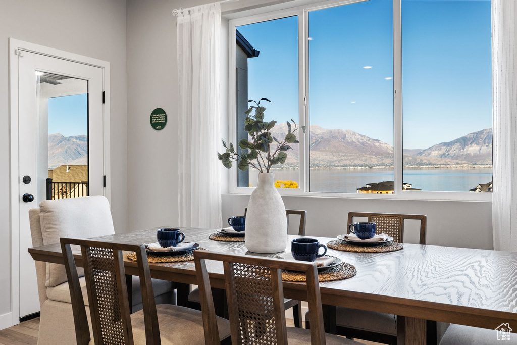 Dining space featuring light hardwood / wood-style floors, a water and mountain view, and a healthy amount of sunlight