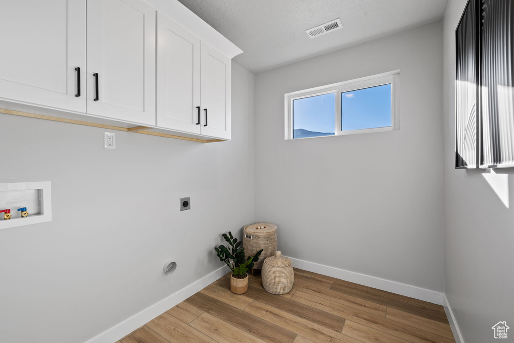 Laundry room with cabinets, electric dryer hookup, hookup for a washing machine, and light hardwood / wood-style floors