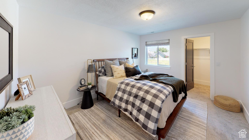 Bedroom featuring a closet, a textured ceiling, light colored carpet, and a spacious closet