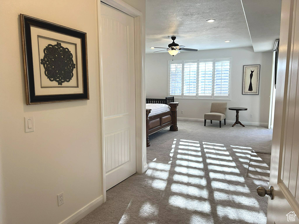Bedroom with a closet, a textured ceiling, light colored carpet, and ceiling fan