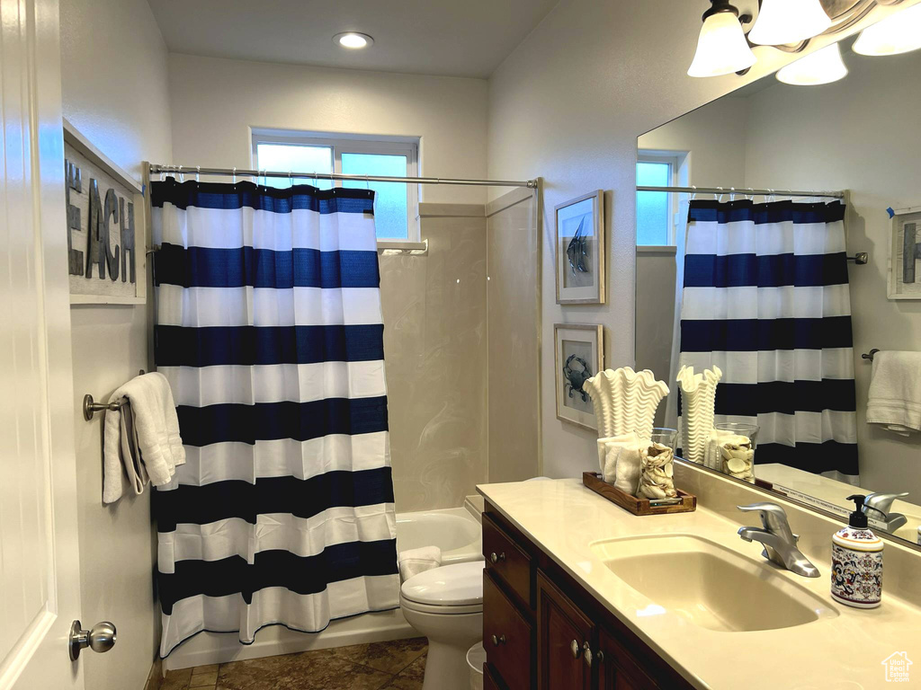 Full bathroom with toilet, vanity with extensive cabinet space, tile flooring, and shower / tub combo