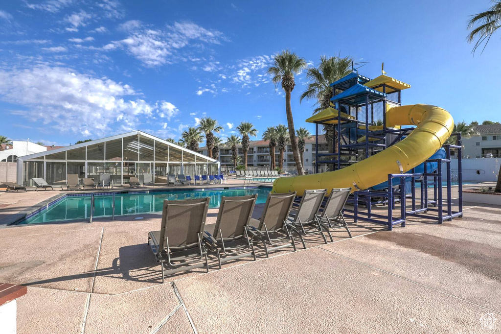 View of swimming pool featuring a playground, a patio area, and a water slide