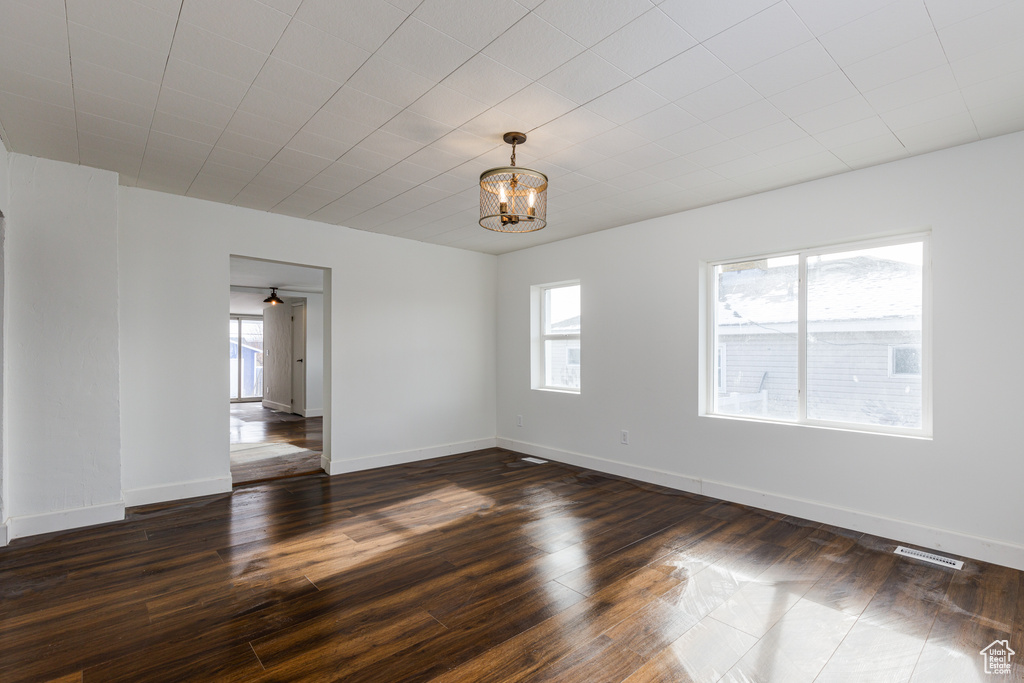 Empty room with a chandelier and dark hardwood / wood-style floors